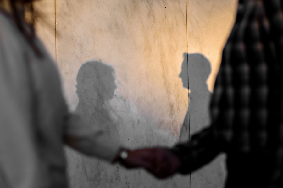 An couple hold hands with their shadows behind them.